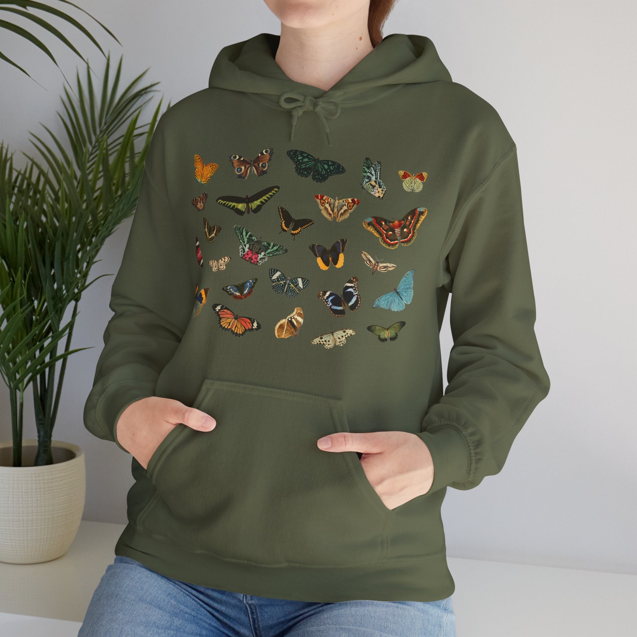 Person wearing a military green hoodie with butterfly designs against a neutral background
