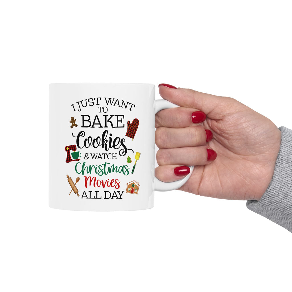 Person holding a white Christmas mug with the quote “I just want to bake cookies and watch Christmas movies all day,” wearing red nail polish.