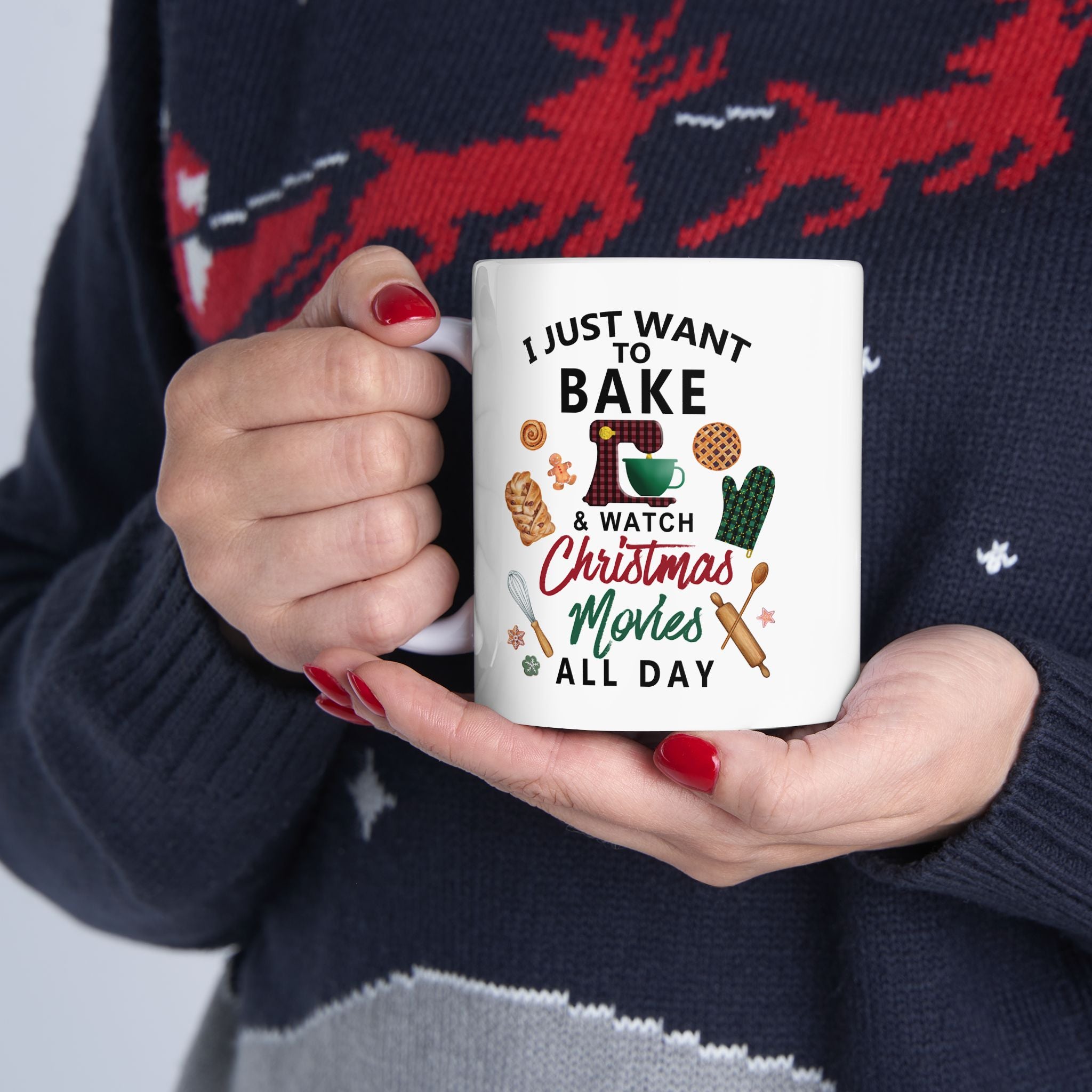 Person holding a mug with baking and Christmas movie text, wearing a festive sweater. Bake Cookies and Watch Christmas Movies. 11 oz coffee cup