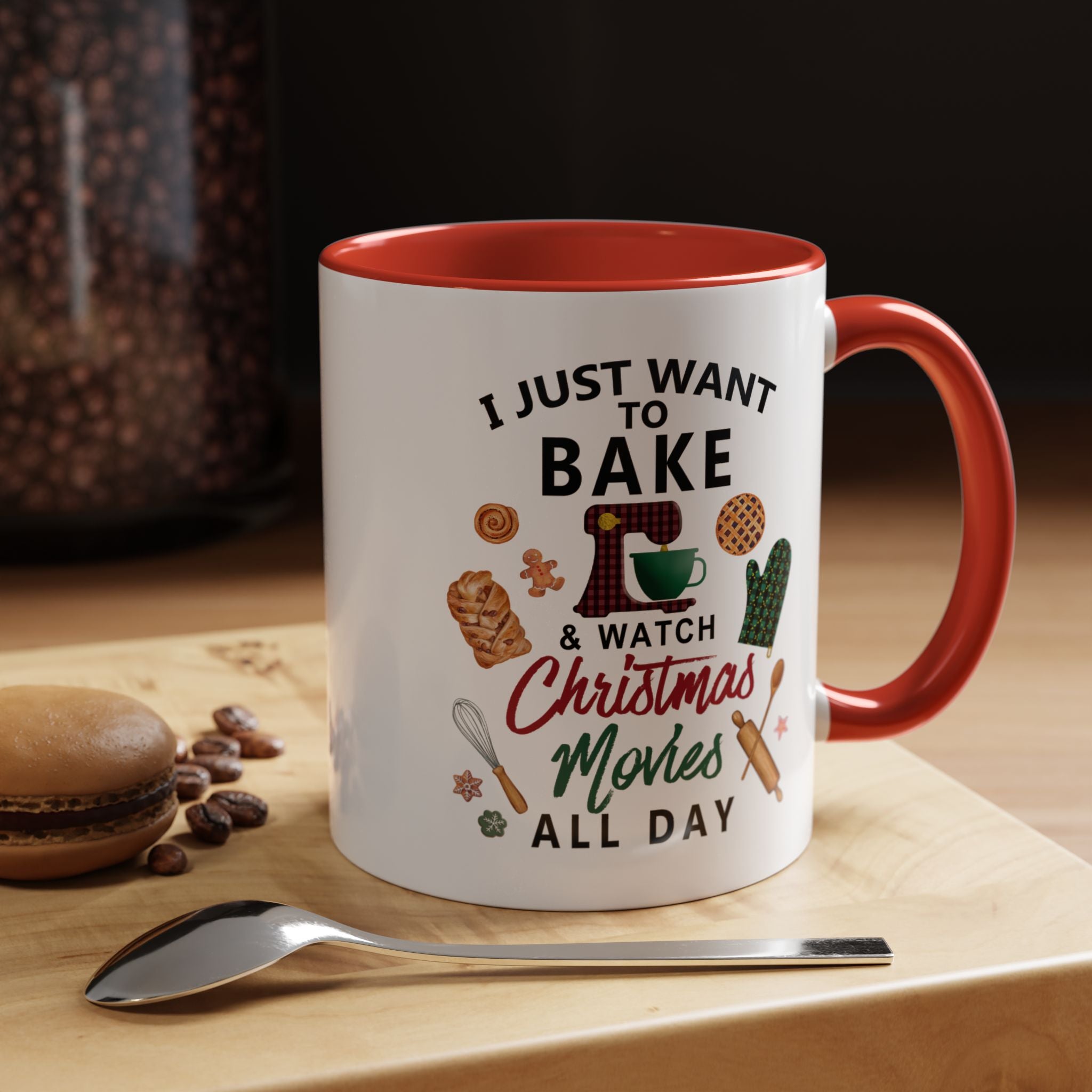 White mug with red interior and handle, featuring text and graphics on a wooden surface with cookies and coffee beans.